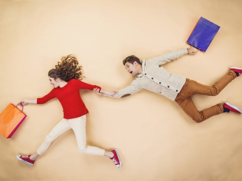 a man and a woman are running with shopping bags