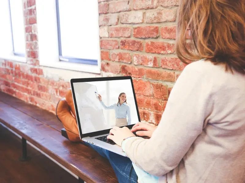a woman is sitting on a bench using a laptop computer
